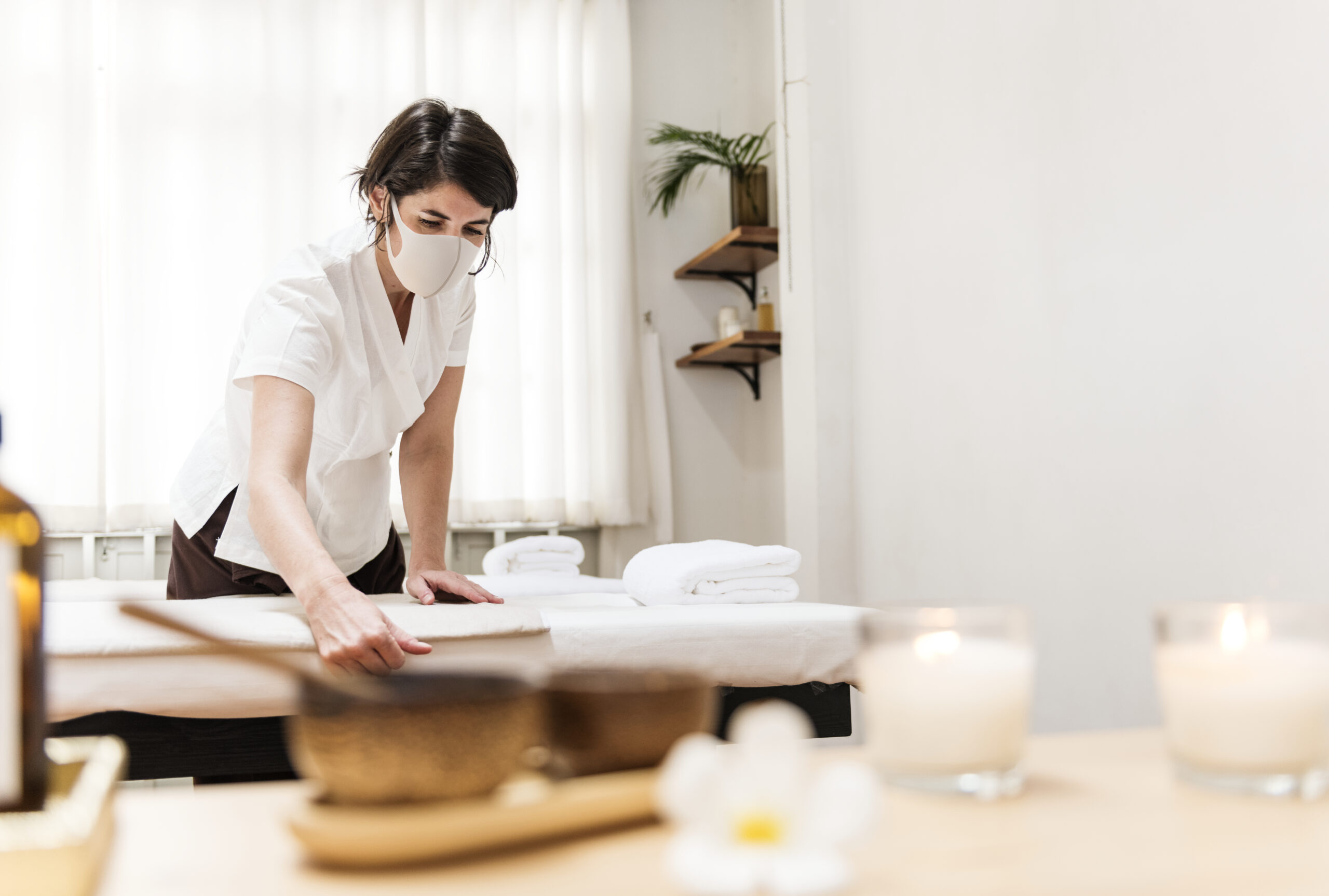 Spa massage therapist with face mask working in the new normal